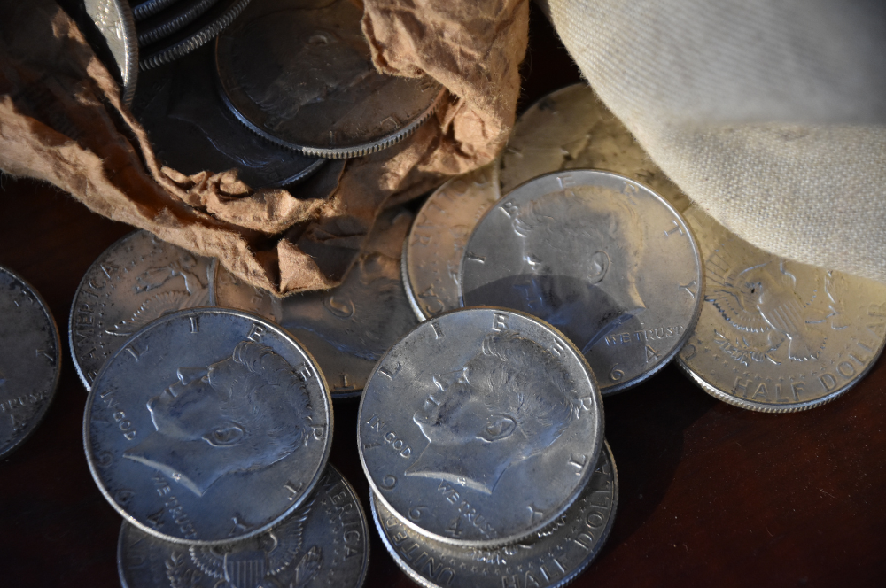 A close-up of silver Kennedy half dollars spilling from a paper roll, captured by Coin Buyers in Midland.